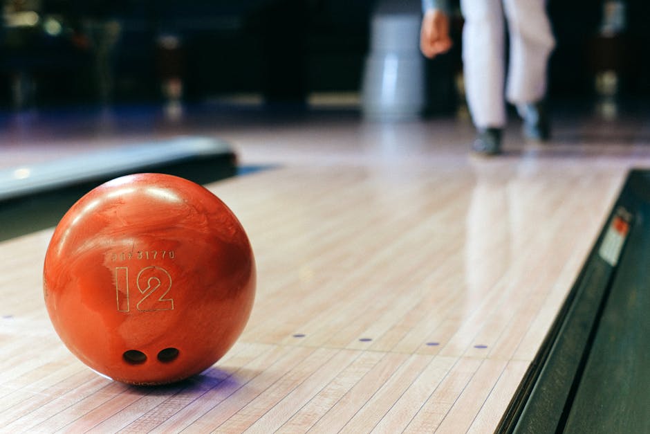 Orange bowling ball with number 12 in the foreground of a lane
